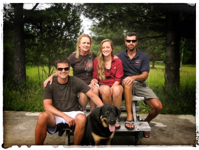 The Rafferty family sitting together on top of a picnic table with their dog at Adirondac Rafting Company